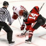 two persons playing ice hockey with referee