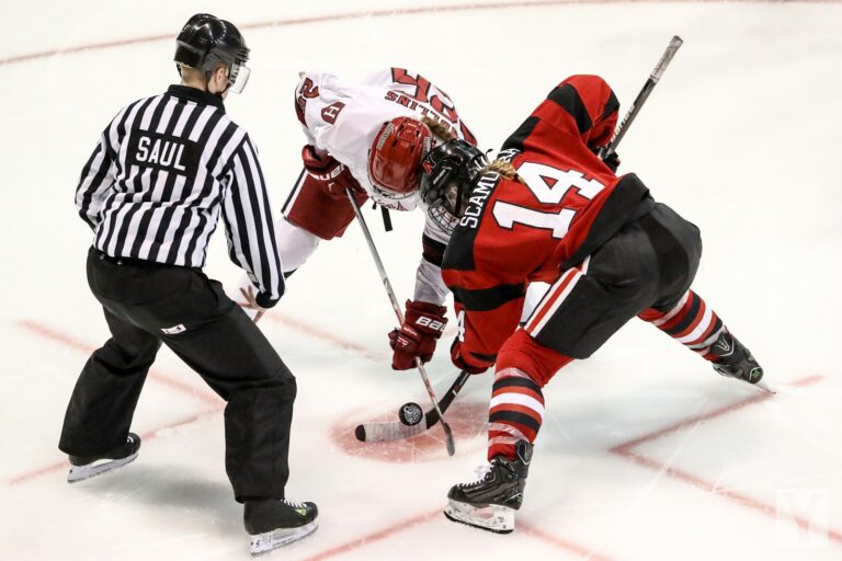 two persons playing ice hockey with referee